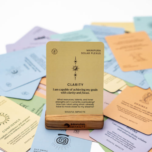 Yellow Chakra Affirmation Card with text on a pile of other cards with different designs and colors