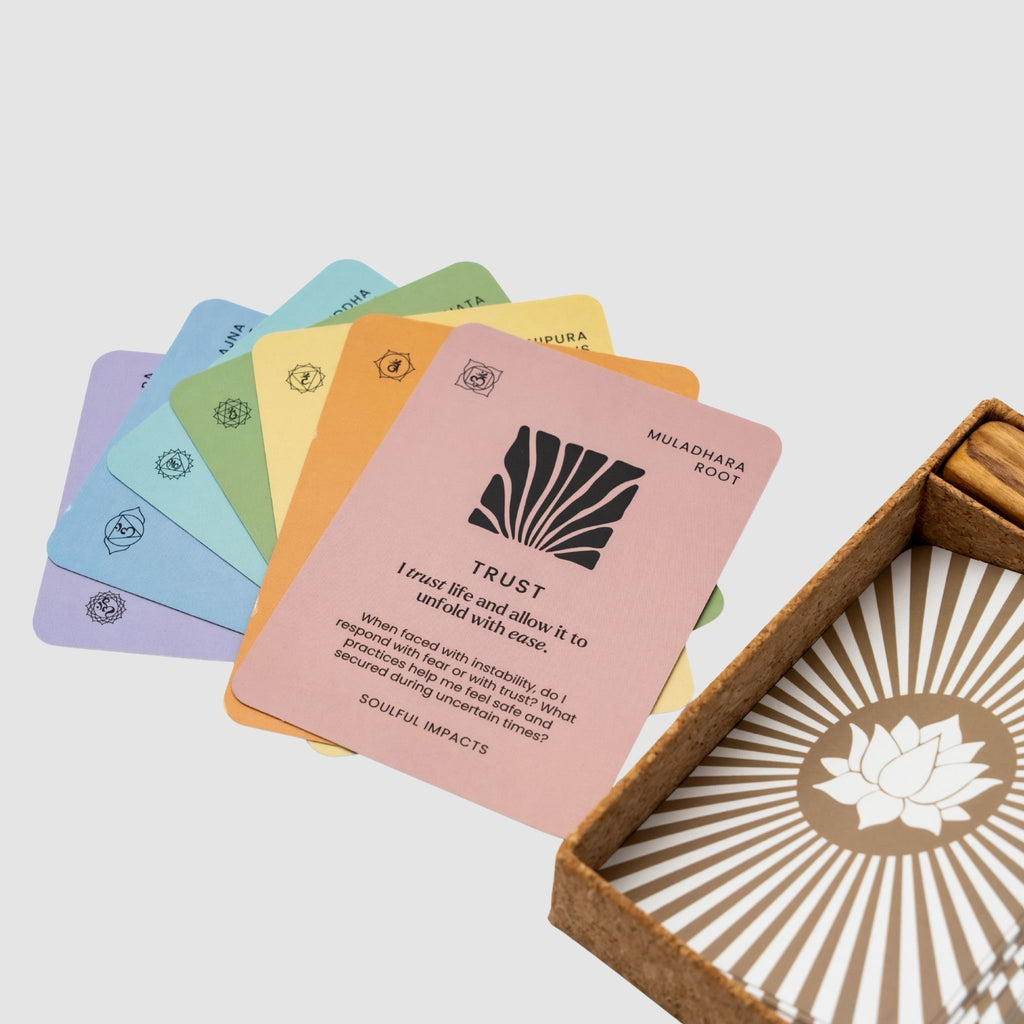 Set of colorful Chakra Affirmation Cards with text on a pile of other cards with different designs and colors with text and symbols, open box with lotus design on a light background