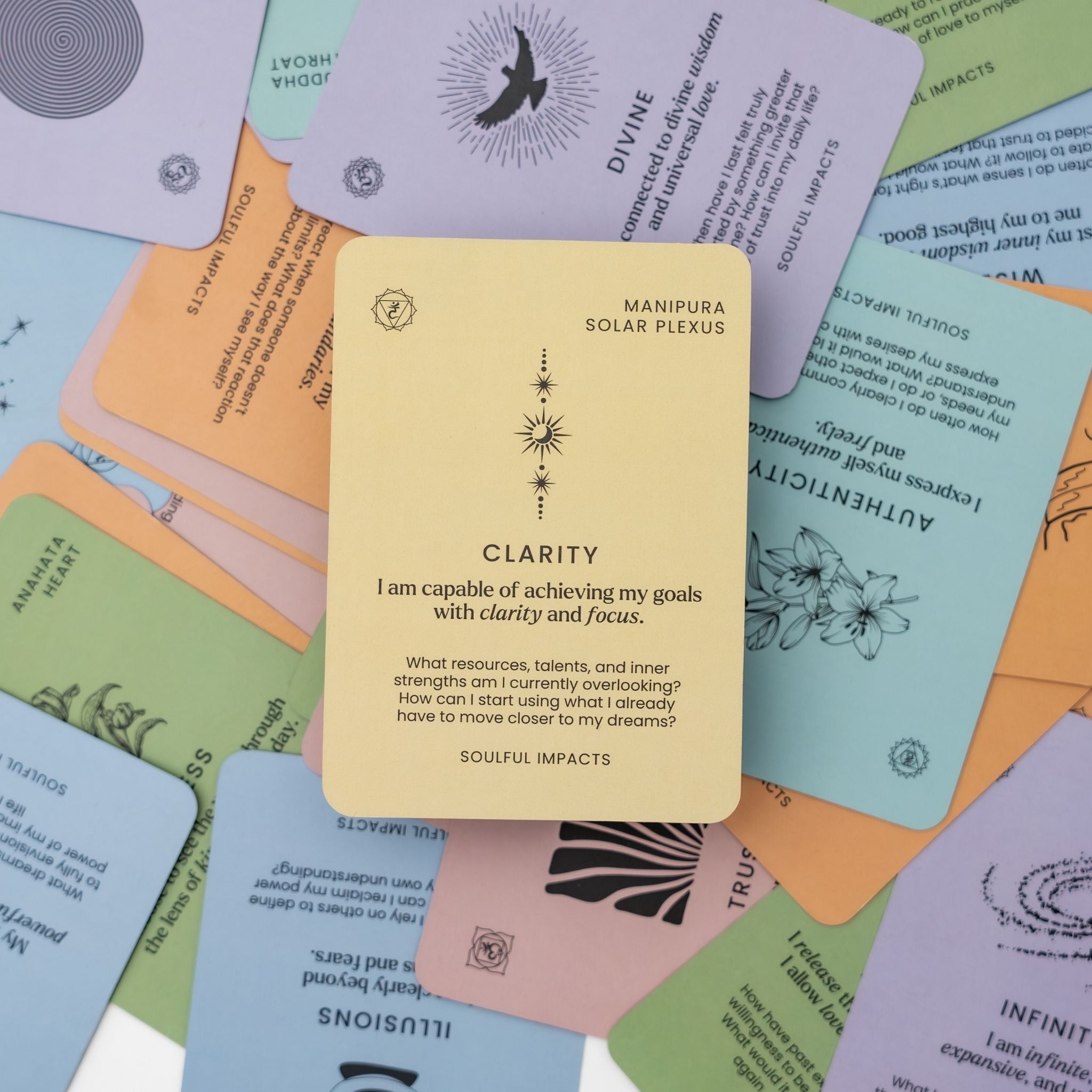 Colorful tarot chakra cards with text and symbols on a background of other colorful cards spread out