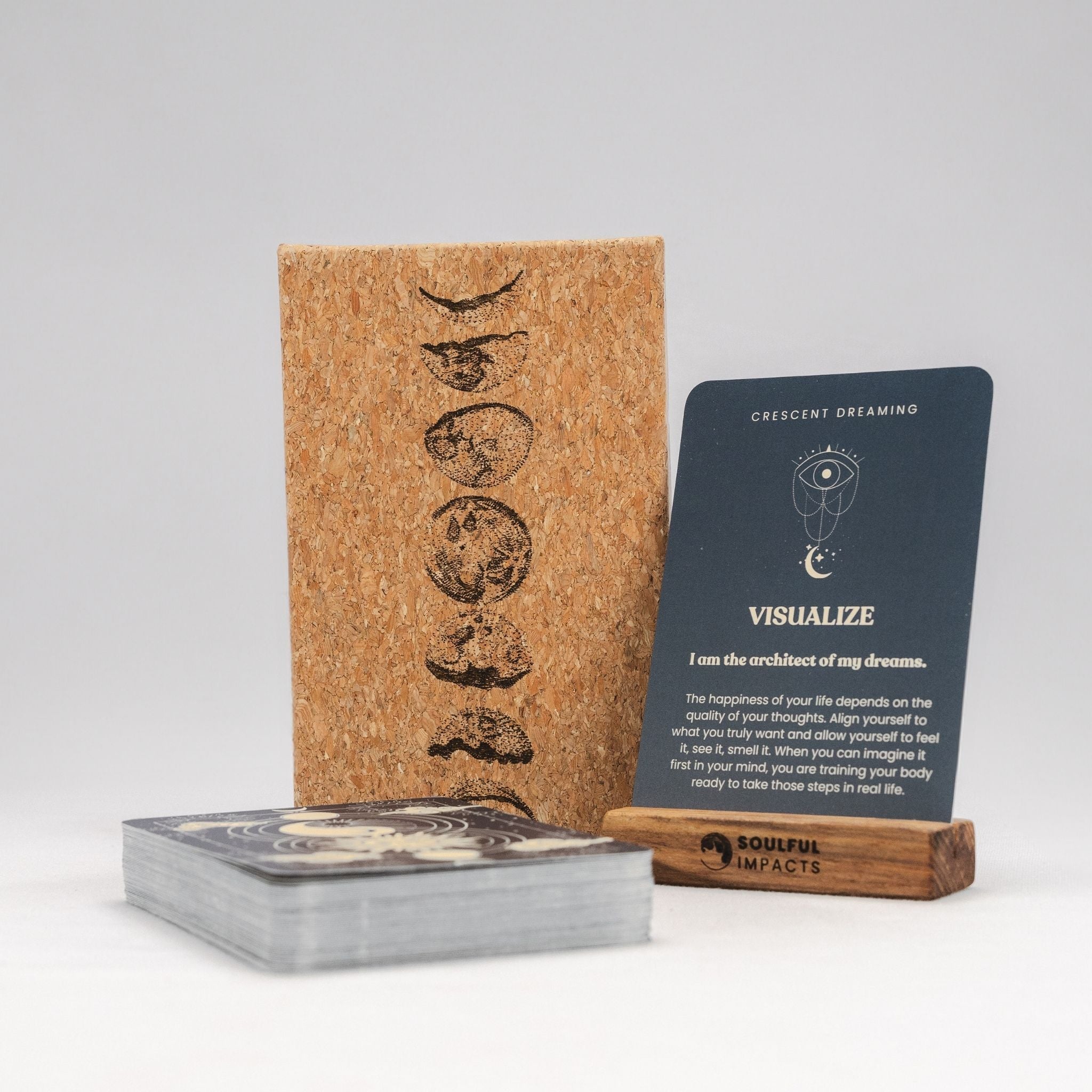 Cork-bound book with tarot cards and a card on a stand against a white background