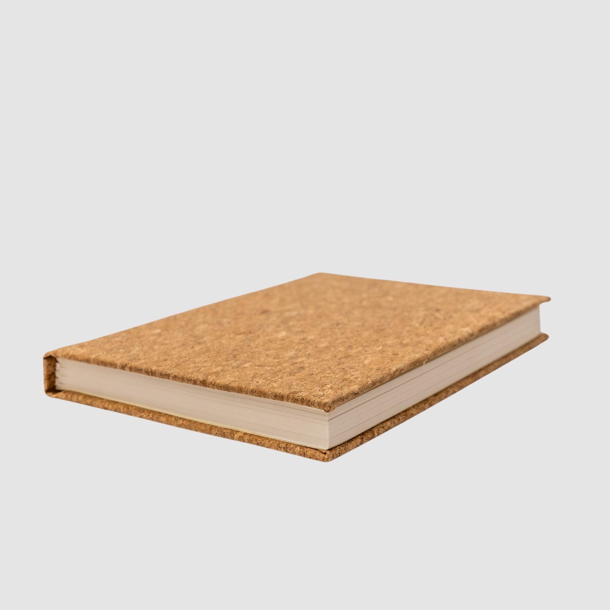 Hardcover, blank, cork-based notebook, sitting tilted on its side, on a white background