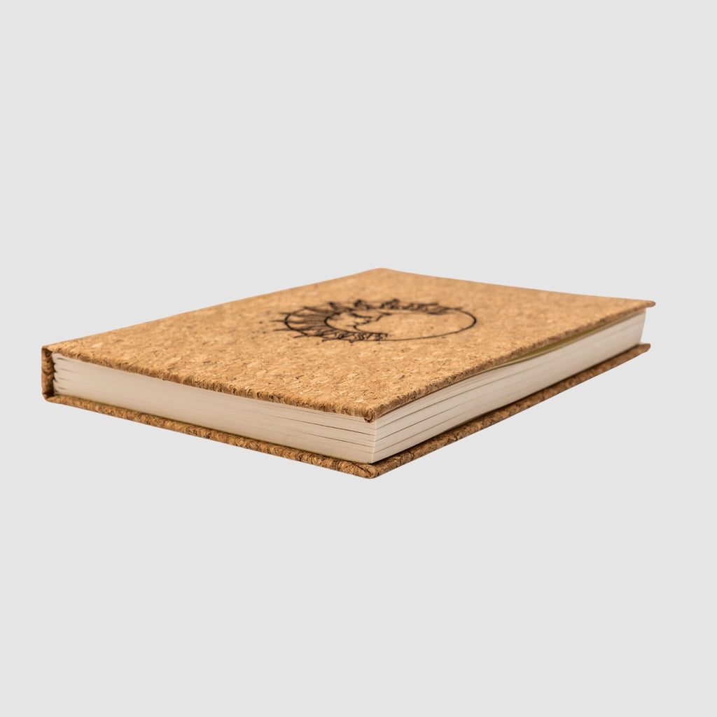 Cork hardcover blank notebook with sun-moon design, sitting tilted on a white background