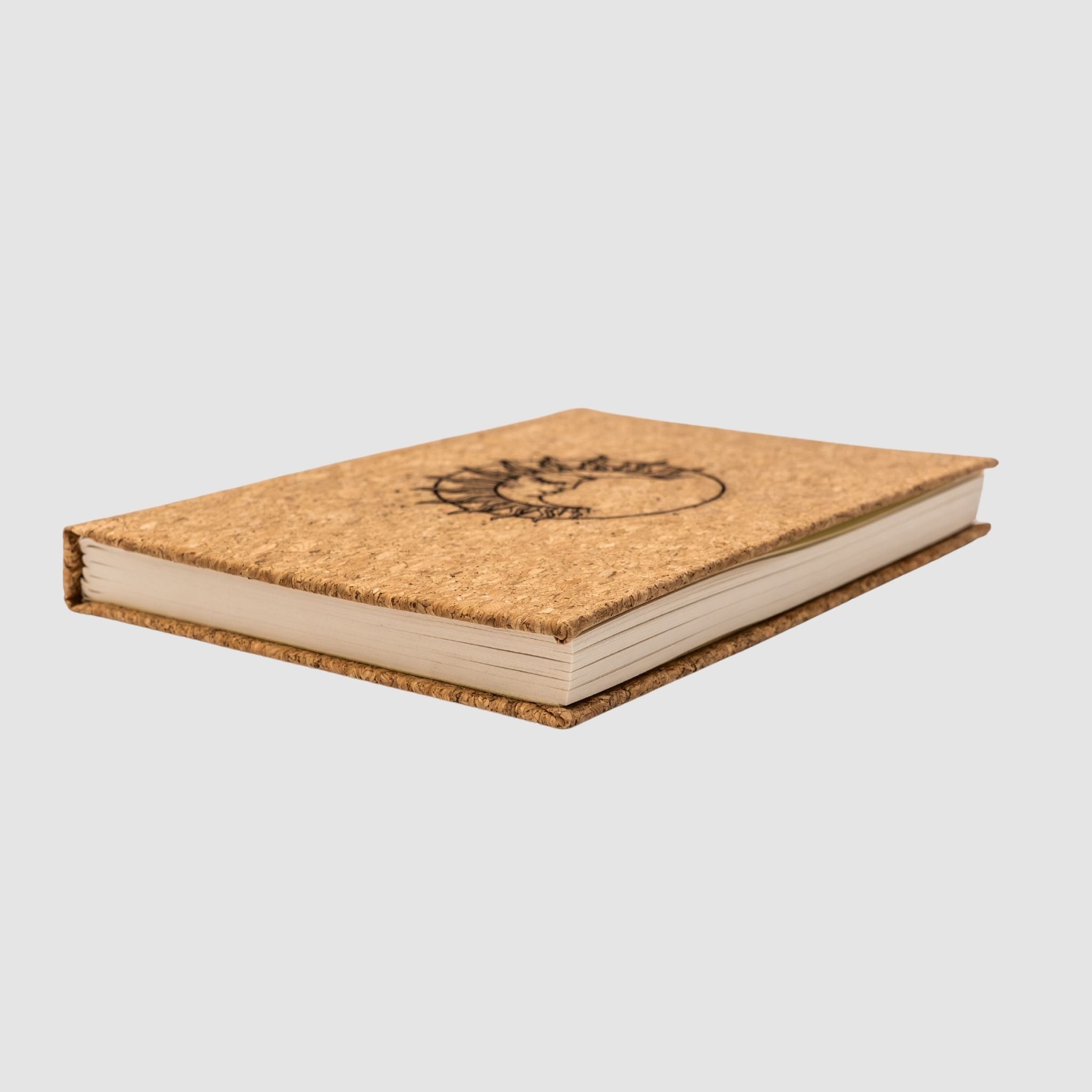 Cork hardcover blank notebook with sun-moon design, sitting tilted on a white background