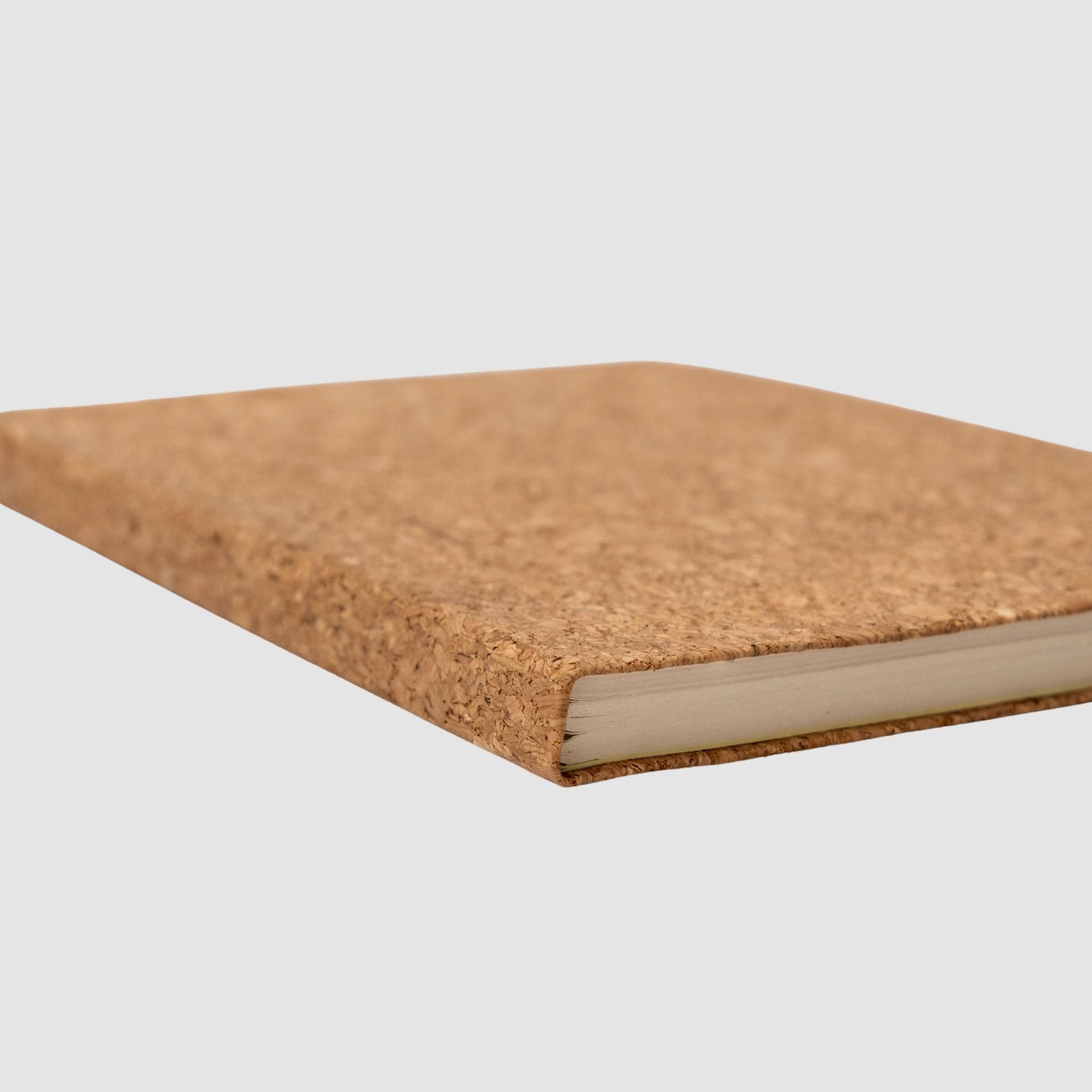 Softcover, blank, cork-based notebook, tilted on its side, on a white background