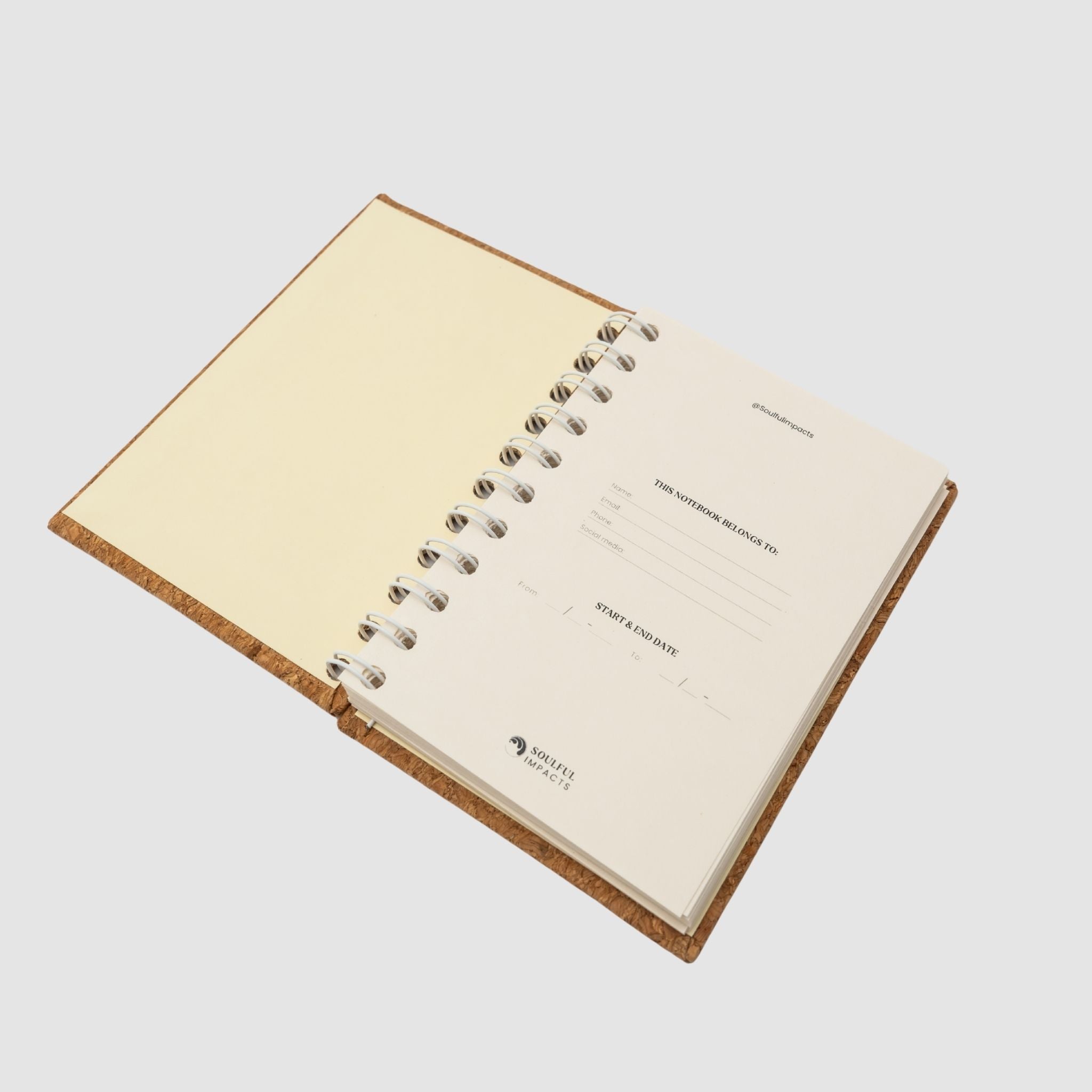 Open small, compact spiral notebook with beige pages, sitting on a white background