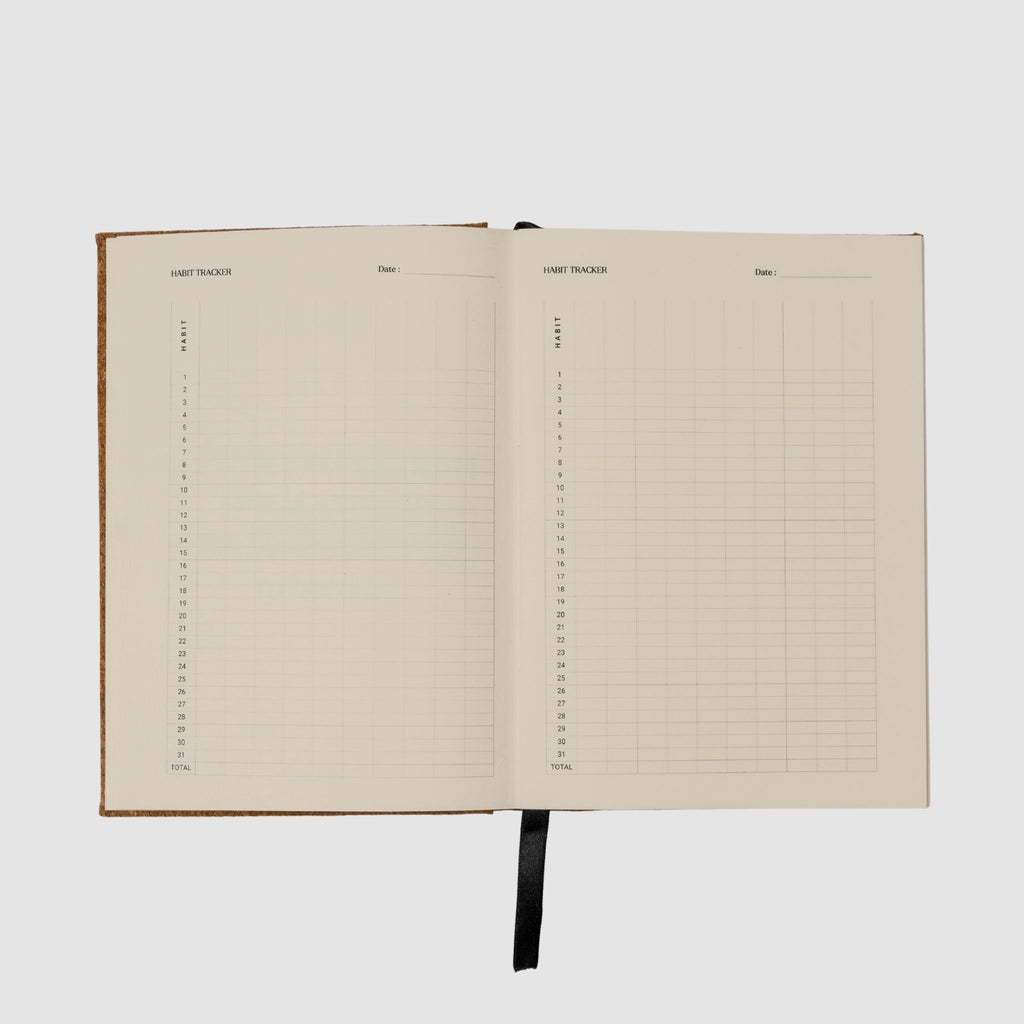 Open notebook with habit tracker grid pages on a white background
